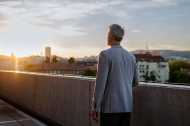 a person in their forties gazing at the horizon, with a sunset and beautiful landscape in the background, symbolizing new opportunities and life phases.