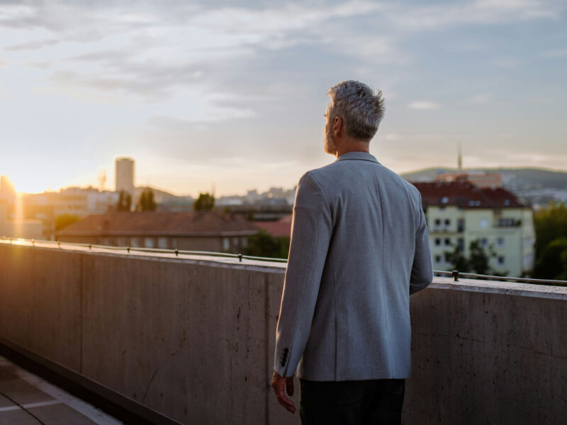 a person in their forties gazing at the horizon, with a sunset and beautiful landscape in the background, symbolizing new opportunities and life phases.