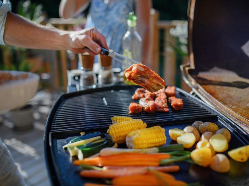 Close-up of a summer BBQ grill with assorted meats and vegetables.