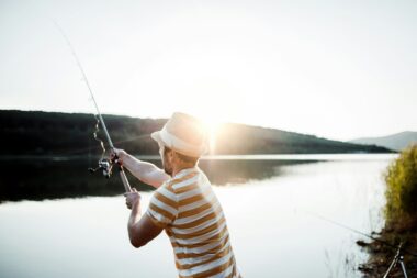 Angler fishing at a serene European lake at dawn, perfect for discovering the best fishing spots in Europe.