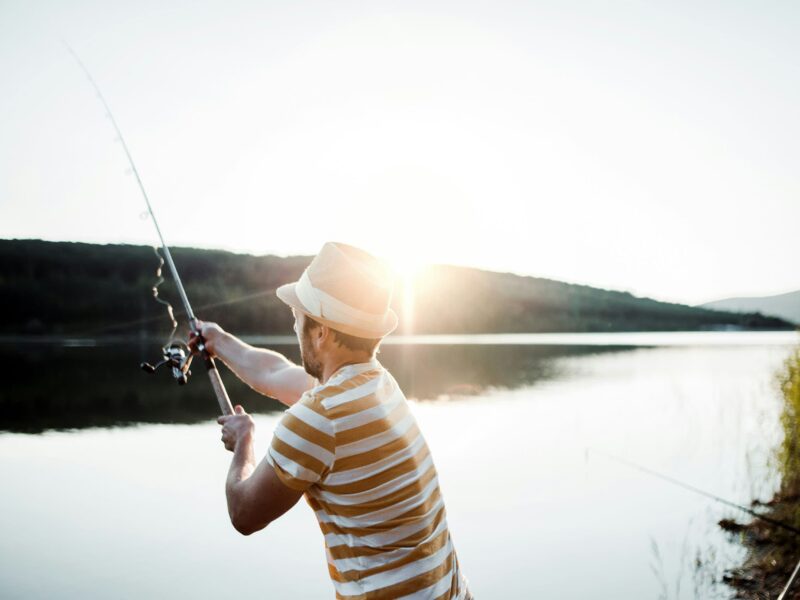 Angler fishing at a serene European lake at dawn, perfect for discovering the best fishing spots in Europe.